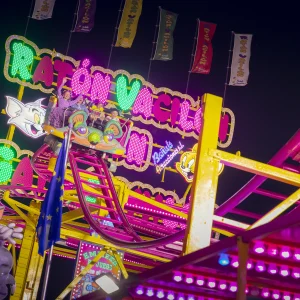 Reportage photo à la Feria de Séville - passagers riant et criant sur le manège, rails et néons du spinning coaster capturé de nuit